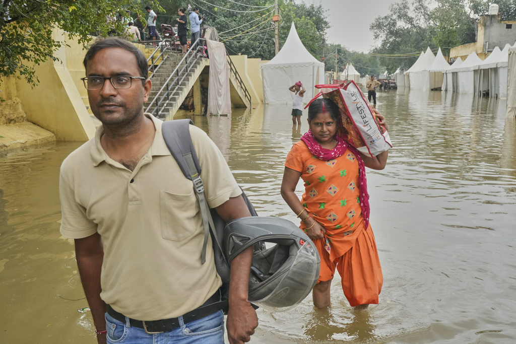 Bindu Pandey, 40, center, wades through the floodwaters of the swollen Yamuna River, leaving behind her inundated home on the banks to seek refuge in a temporary shelter, in New Delhi, India, Friday, Sept. 5, 2025. (AP Photo/Manish Swarup)