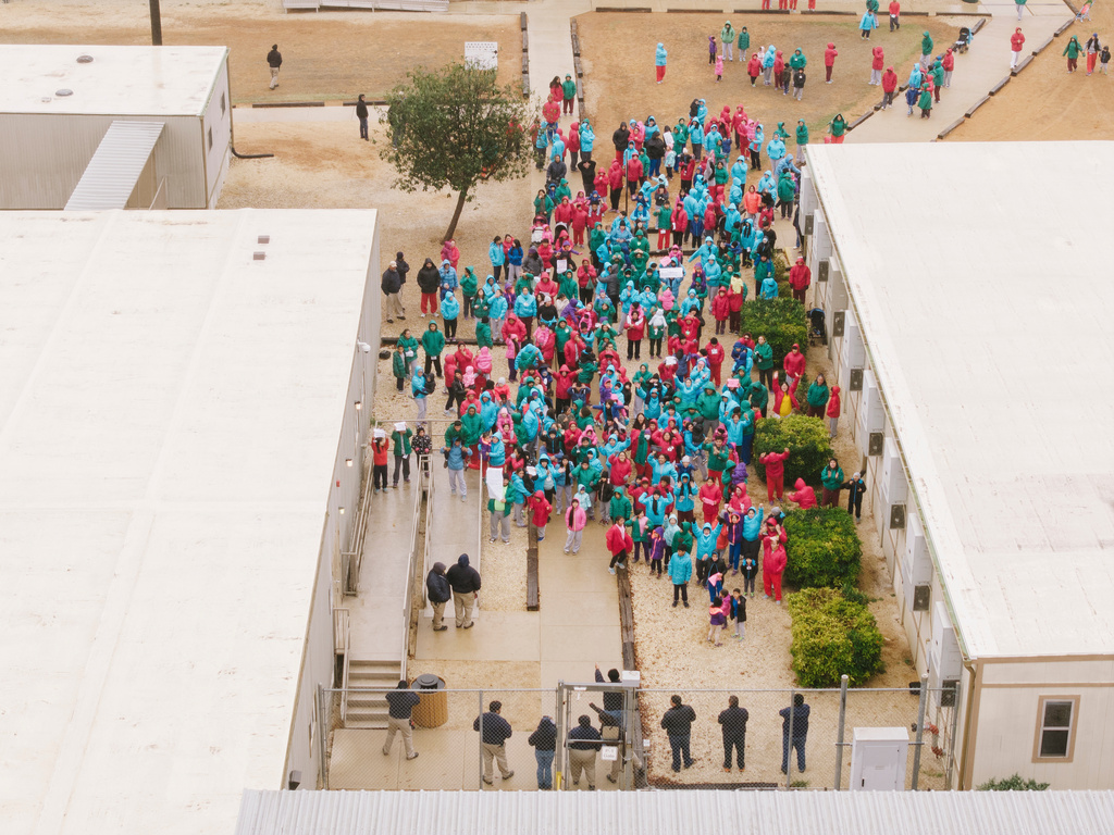 Detainees held at the South Texas Family Residential Center wave signs during a demonstration in Dilley, Texas, Saturday, Jan. 24, 2026. (AP Photo/Brenda Bazán)