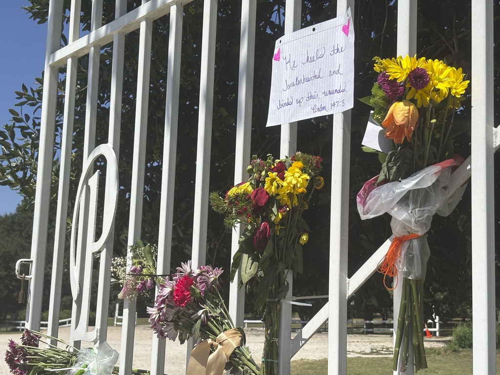 Flowers and memorial notes hang from the gate to Kiesel Park in Auburn, Ala., Tuesday Sept. 9, 2025 as a memorial to Julie Gard Schnuelle. (AP Photo/Kimberly Chandler)