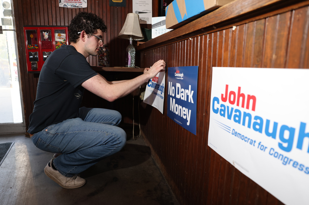 Gabe Kaplan, deputy finance director for State Sen. John Cavanaugh's campaign, posts signs in Underwood Bar ahead the election night watch party for the Democratic nomination to the House of Representatives in Nebraska's second district, Tuesday, May 12, 2026, in Omaha, Neb. (AP Photo/Rebecca S. Gratz)