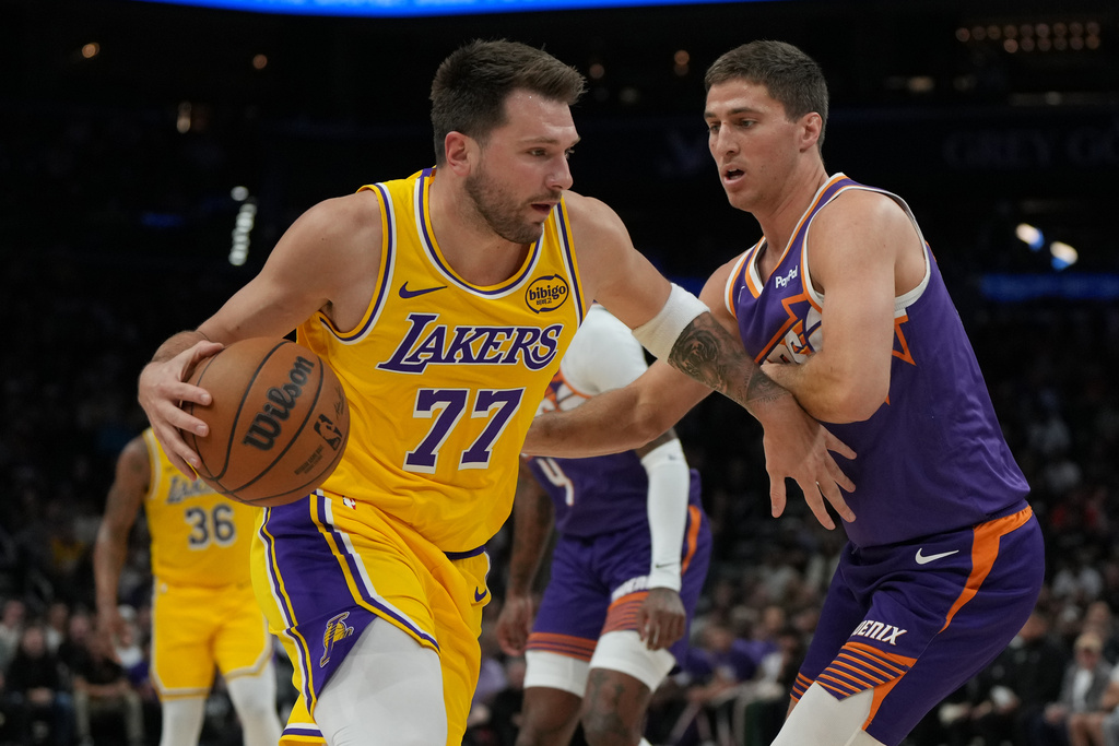 Los Angeles Lakers guard Luka Doncic (77) shields the ball from Phoenix Suns guard Collin Gillespie during the first half of an NBA basketball game, Thursday, Feb. 26, 2026, in Phoenix. (AP Photo/Rick Scuteri)