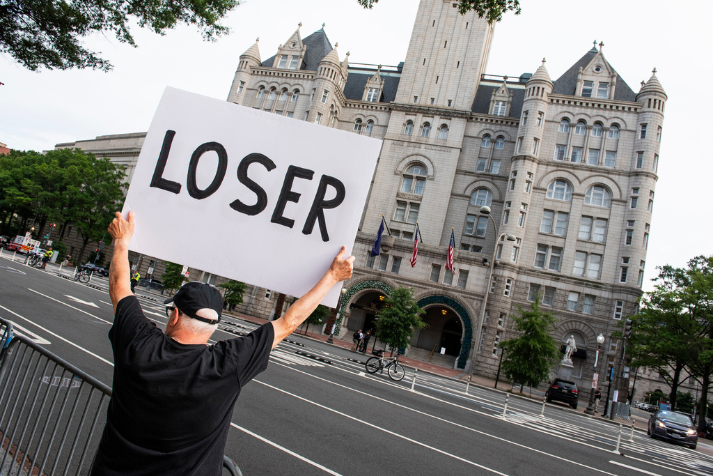 A demonstrator holds up a sign outside the Waldorf Astoria Hotel in Washington, site of the White House Correspondents' Dinner, Friday, July 24, 2026. (AP Photo/Cliff Owen)