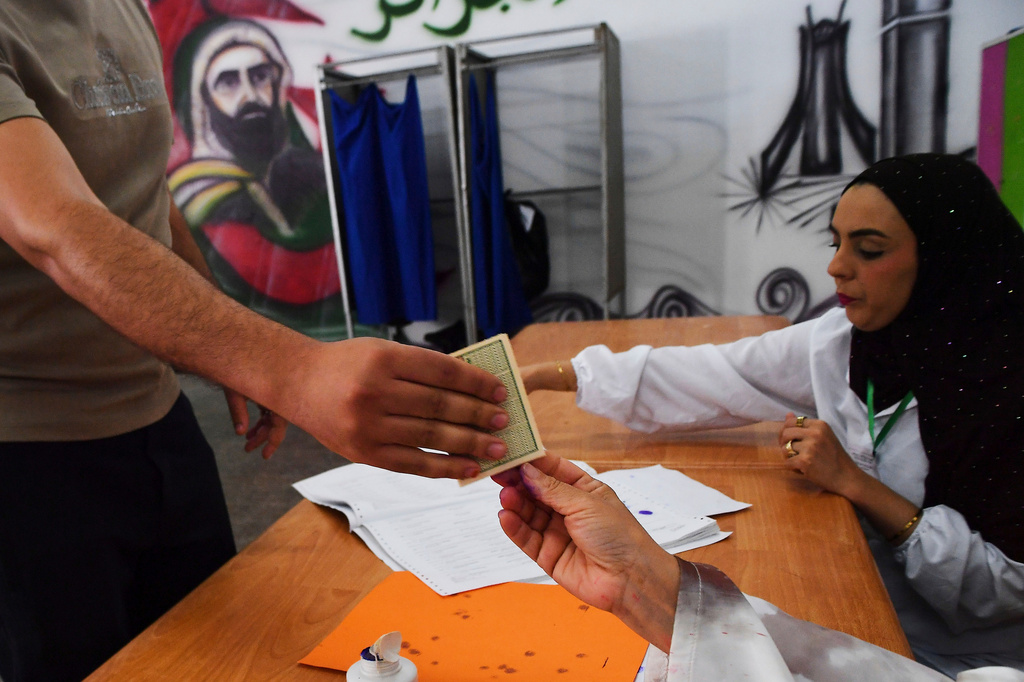 A man hands over his document to election workers during the parliamentary elections in Algiers, Algeria, Thursday, July 2, 2026. (AP Photo/Fateh Guidoum)
