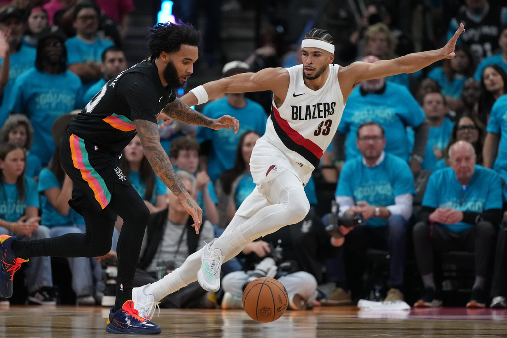 San Antonio Spurs forward Julian Champagnie (30) drives against Portland Trail Blazers forward Toumani Camara (33) during the first half in Game 1 of a first-round NBA playoffs basketball series in San Antonio, Sunday, April 19, 2026. (AP Photo/Eric Gay)