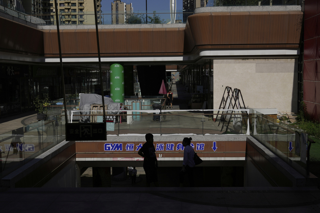 People stands in a partially shuttered Evergrande commercial complex, in Beijing, China, Monday, Aug. 25, 2025. (AP Photo/Mahesh Kumar A.)