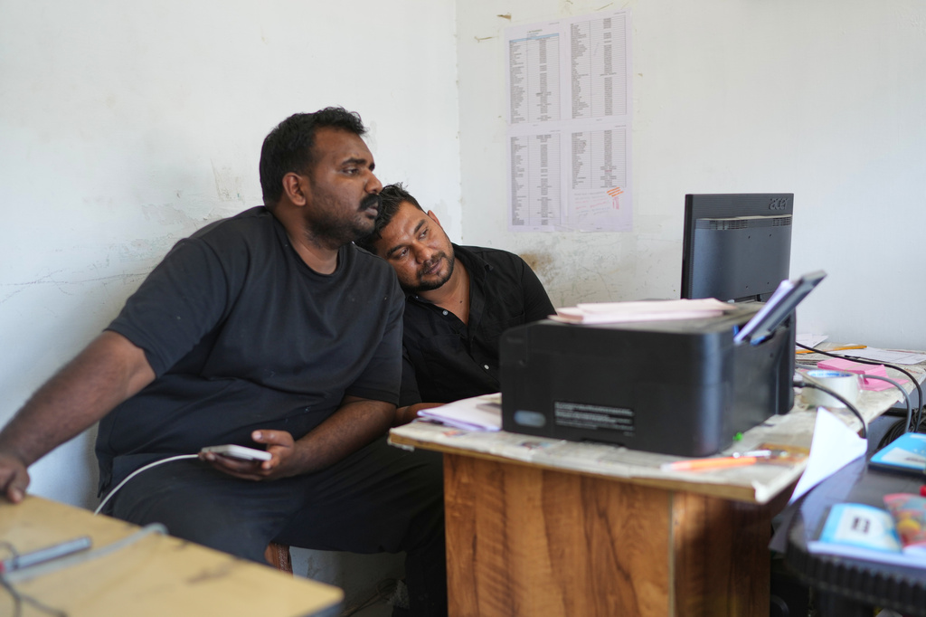 Safeer Mohammed Koorimannil, right, leans on the shoulder of his brother, Jouhar Babu, while working at their CM Fisheries office in Sulthan Bathery in the southern state of Kerala, India, Thursday, March 12, 2026. (AP Photo/Manish Swarup)