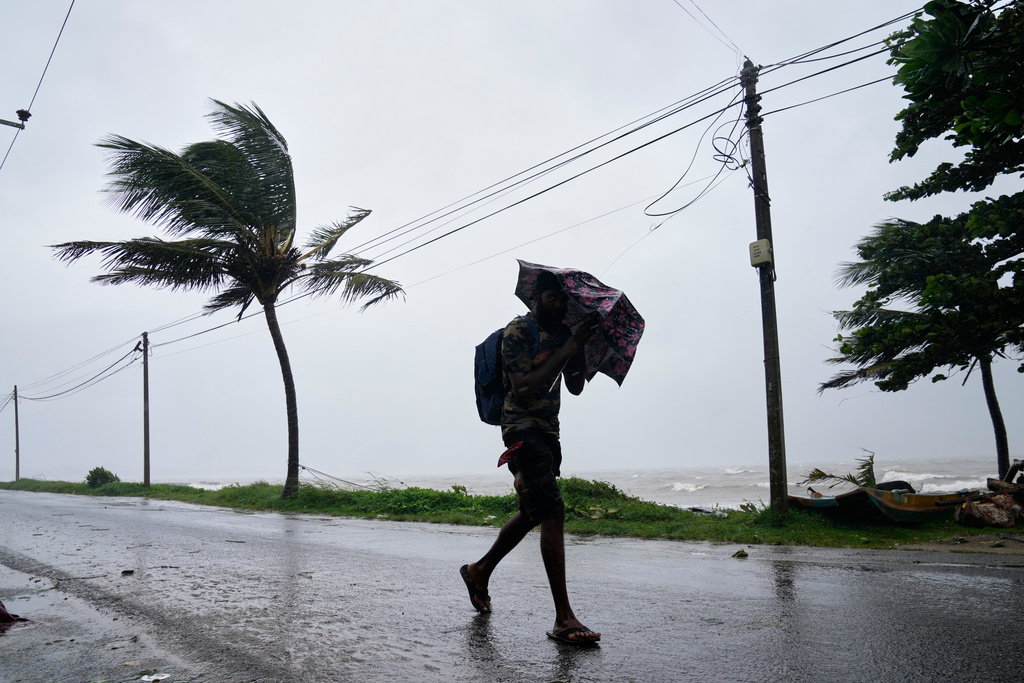 A man walks under a heavy downpour in Colombo, Sri Lanka, Friday, Nov. 28, 2025. (AP Photo/Eranga Jayawardena)