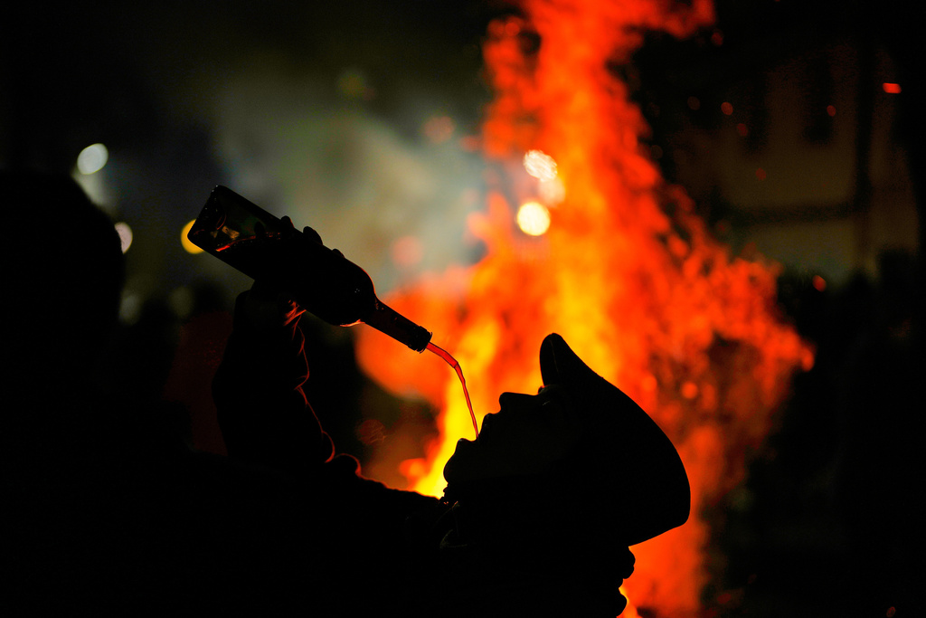 An assistant drinks wine from a bottle during a ritual in honor of Saint Anthony the Abbot, the patron saint of domestic animals, in San Bartolome de Pinares, Spain, Friday, Jan. 16, 2026. (AP Photo/Manu Fernandez)