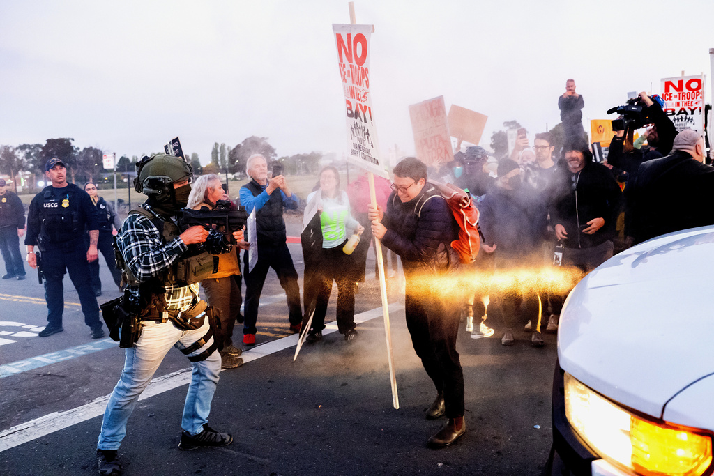 A person clears protesters blocking a caravan of U.S. Customs and Border Protection personnel trying to enter Coast Guard Base Alameda on Thursday, Oct. 23, 2025, in Oakland, Calif. (AP Photo/Noah Berger)