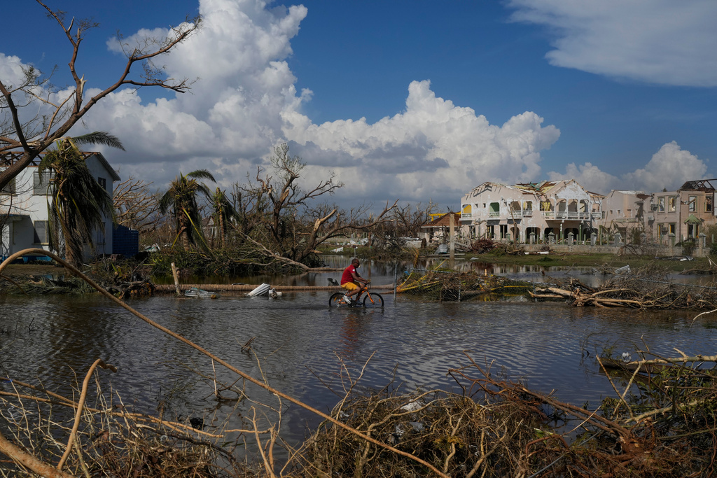 A man rides his bicycle through an inundated street in Black River, Jamaica, Thursday, Oct. 30, 2025, in the aftermath of Hurricane Melissa. (AP Photo/Matias Delacroix)