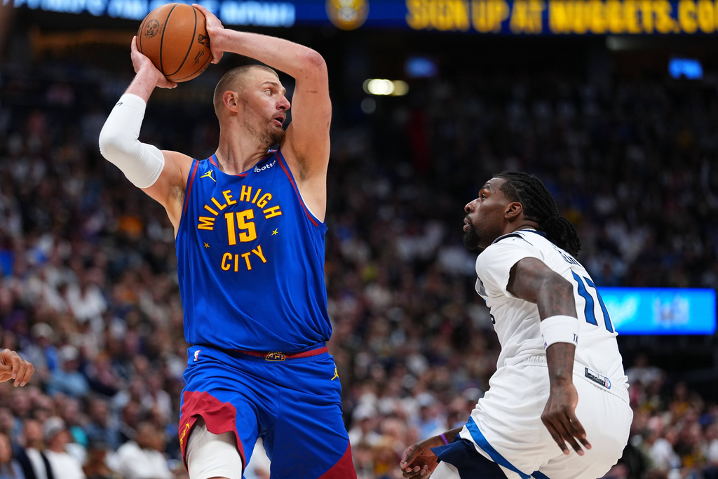 Denver Nuggets center Nikola Jokic (15) looks to pass the ball over Minnesota Timberwolves center Naz Reid, right, during the first half in Game 2 of a first-round NBA playoffs basketball series Monday, April 20, 2026, in Denver. (AP Photo/Jack Dempsey)