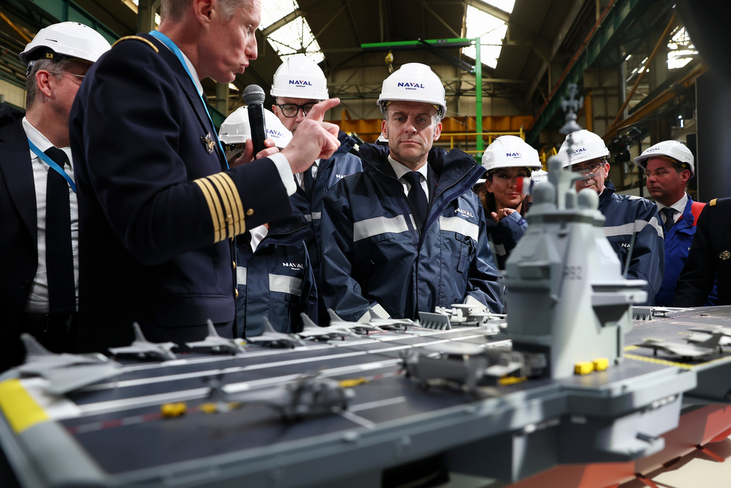 French President Emmanuel Macron, center, stands next to the model of a ship named "France Libre", during his visit to the construction site of Naval Group Nantes-Indret, where the next generation of French aircraft carrier is under construction, in Indret, France, Wednesday, March 18, 2026. (Gonzalo Fuentes/Pool Photo via AP)