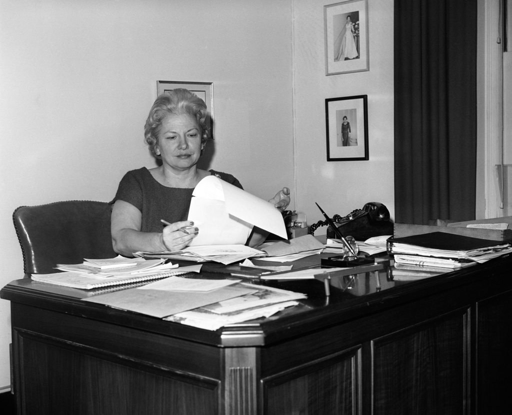 FILE - Liz Carpenter, press secretary and staff director for first lady Lady Bird Johnson, poses for a photo in her office in the East Wing of the White House in Washington, D.C., Dec. 9, 1963. On the walls are her Theta Sigma Phi Headliner Award and two photos of Mrs. Lyndon B. Johnson. (AP Photo/Harvey Georges, File)