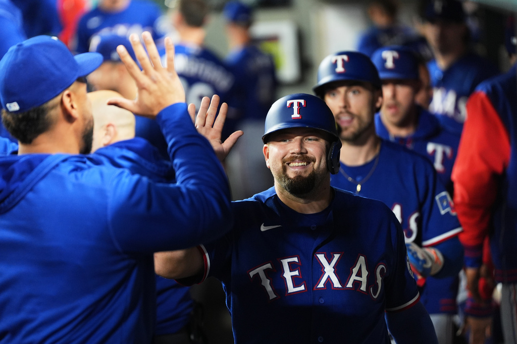 Texas Rangers' Jake Burger is greeted in the dugout after scoring on a two-run single from Justin Foscue during the fourth inning of a baseball game against the Seattle Mariners, Tuesday, Sept. 8, 2026, in Seattle. (AP Photo/Lindsey Wasson)
