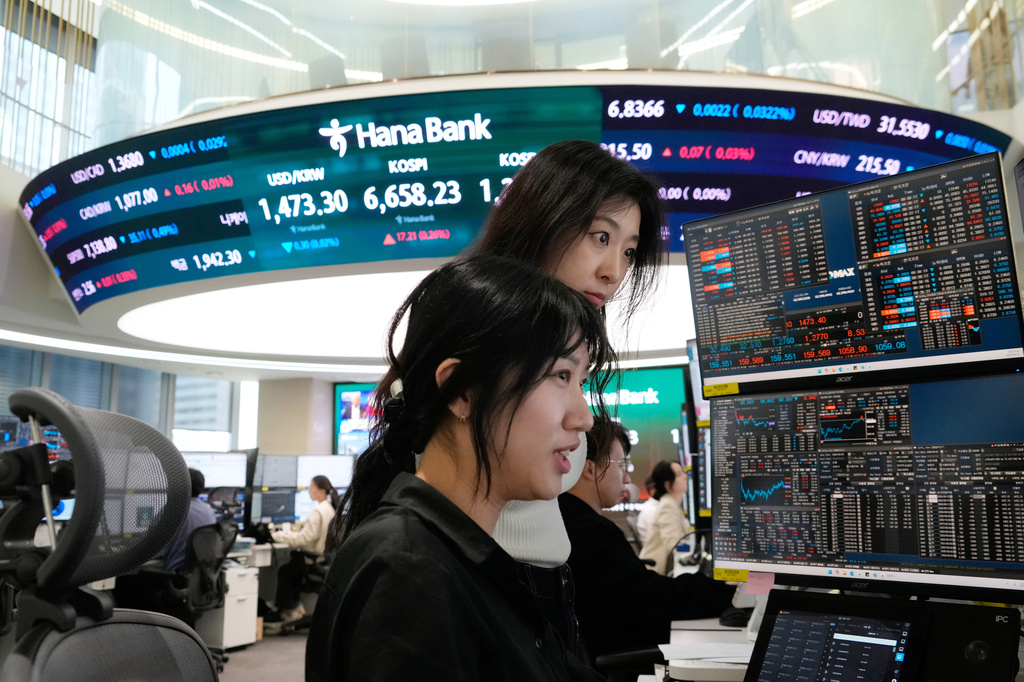 Currency traders watch monitors near a screen showing the Korea Composite Stock Price Index (KOSPI), top center, and the foreign exchange rate between U.S. dollar and South Korean won, top center left, at the foreign exchange dealing room of the Hana Bank headquarters in Seoul, South Korea, Wednesday, April 29, 2026. (AP Photo/Ahn Young-joon)