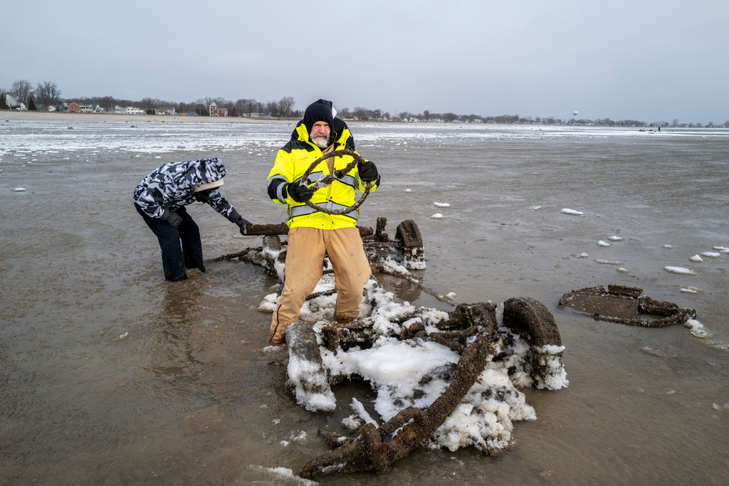 Neil Wakeman, a Luna Pier city council member, holds up a steering wheel as he and friends look over a car that is normally submerged in roughly eight feet of water, about 100 yards off the beach in Luna Pier, Mich., Monday, Dec. 29, 2025. (Andy Morrison/Detroit News via AP)