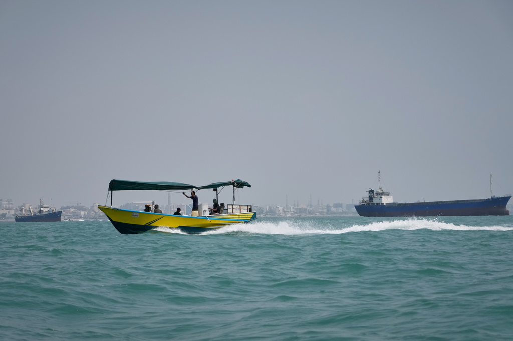 People travel on a motorboat past commercial vessels anchored in the Strait of Hormuz off Bandar Abbas, Iran, with the city's skyline in the background, Sunday, Sept. 6, 2026. (AP Photo/Vahid Salemi)