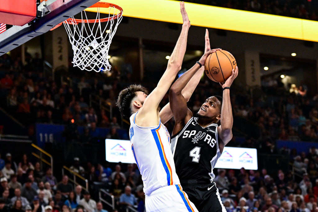 San Antonio Spurs guard De'Aaron Fox (4) shoots against Oklahoma City Thunder Chet Holmgren (7) during the first half of an NBA basketball game, Thursday, Dec. 25, 2025, in Oklahoma City. (AP Photo/Gerald Leong)