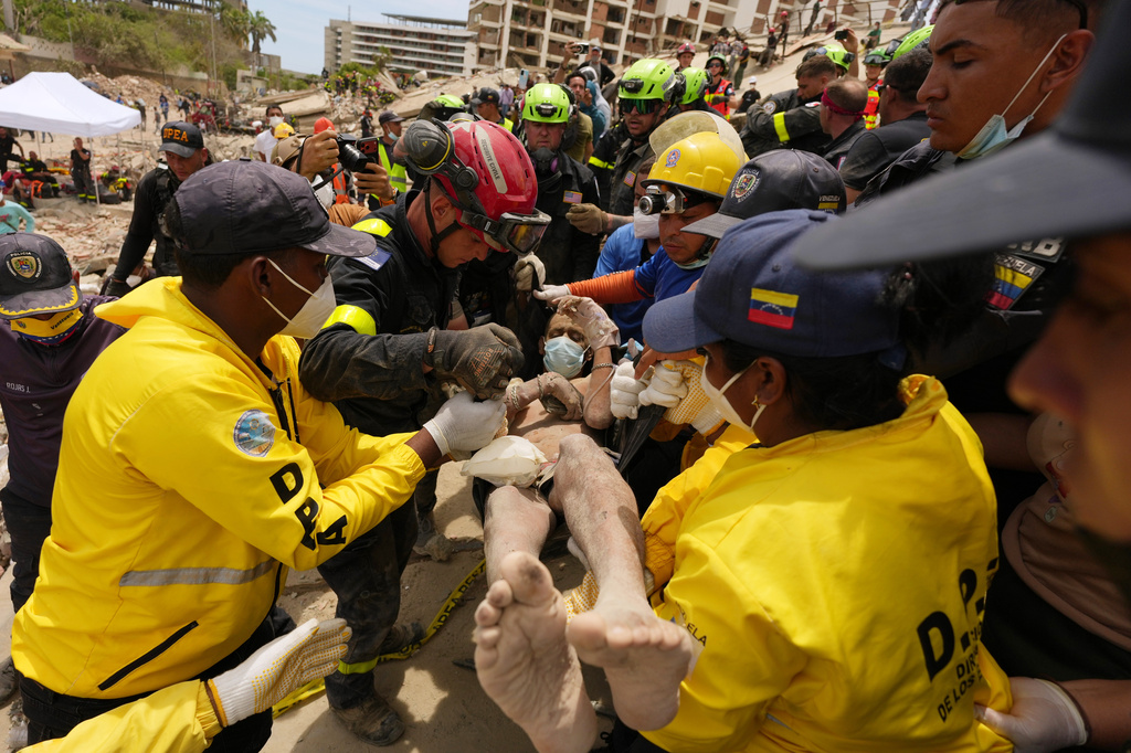 Relief workers carry a man rescued from a building that collapsed in the earthquakes that struck La Guaira, Venezuela, Sunday, June 28, 2026. (AP Photo/Matias Delacroix)