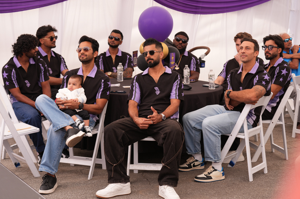 Unmurkt Chand holds his baby, Krishay, with members of the Los Angeles Knight Riders, cricket team form a LA sign with their hands as they pose for a picture at the Pomona Fairplex on Wednesday, April 22, 2026, during the groundbreaking ceremony of the new Knight Riders Cricket Field, which will serve as the Los Angeles Knight Riders' official home field for 2026 and later host cricket at the LA 2028 Olympics. (AP Photo/Damian Dovarganes)