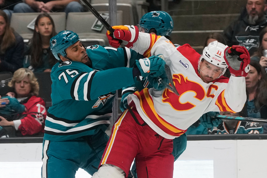 San Jose Sharks right wing Ryan Reaves (75) hits Calgary Flames center Mikael Backlund (11) during the first period of an NHL hockey game in San Jose, Calif., Thursday, Feb. 26, 2026. (AP Photo/Jeff Chiu)