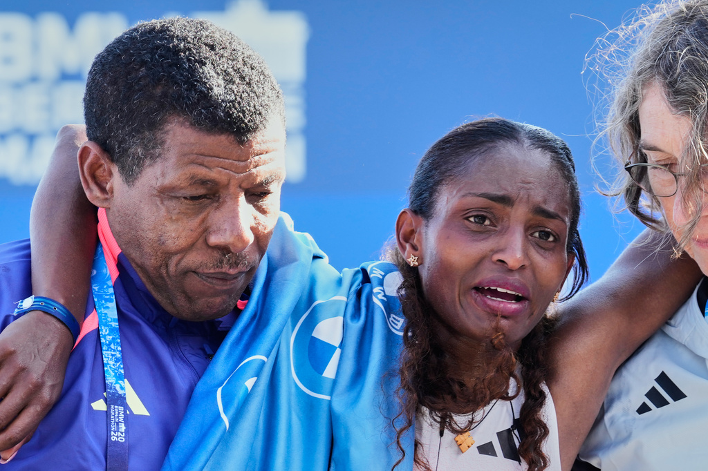 Ethiopia's Tigist Assefa is lead away by former runner Haile Gebrselassie, left, after winning the Berlin Marathon in Berlin, Germany, Sunday, Sept. 27, 2026. (AP Photo/Ebrahim Noroozi)