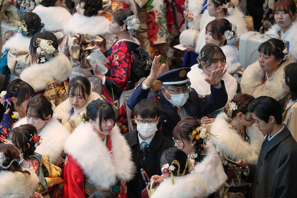 A security person controls the flow of the young adults celebrate the Coming-of-Age Day, a centuries-old tradition and national holiday marking the milestone from childhood to adulthood, Monday, Jan. 12, 2026, in Yokohama near Tokyo. (AP Photo/Eugene Hoshiko)