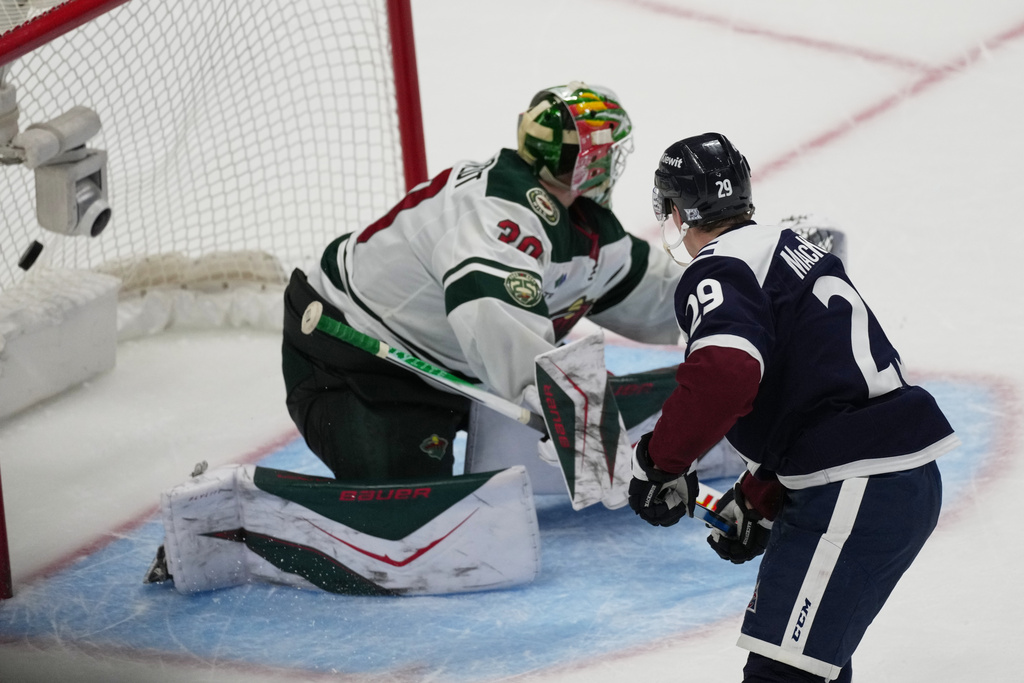 Colorado Avalanche center Nathan MacKinnon, front, scores the winning goal past Minnesota Wild goaltender Jesper Wallstedt during the shootout of an NHL hockey game, Sunday, March 8, 2026, in Denver. (AP Photo/David Zalubowski)