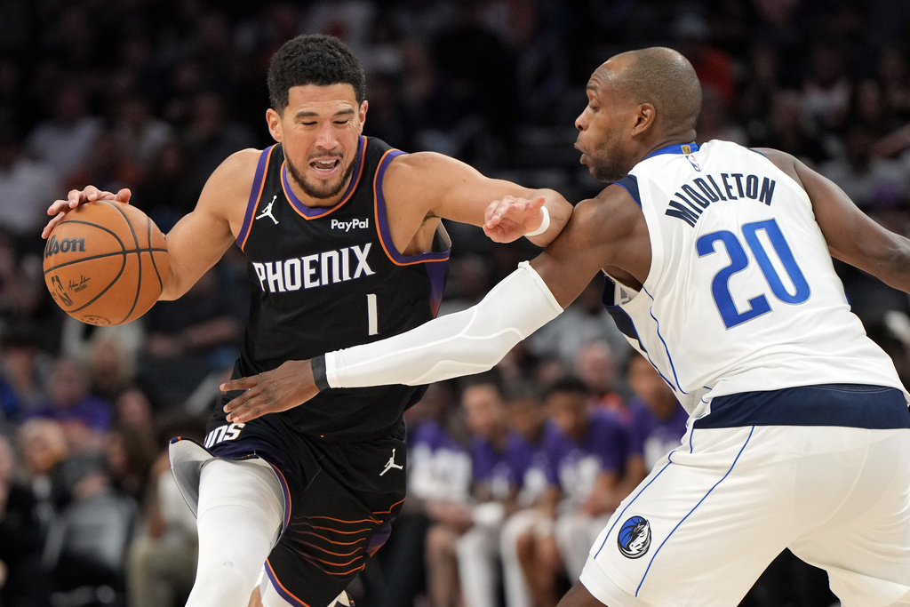 Phoenix Suns guard Devin Booker drives on Dallas Mavericks forward Khris Middleton (20) during the second half of an NBA basketball game, Tuesday, Feb. 10, 2026, in Phoenix. (AP Photo/Rick Scuteri)