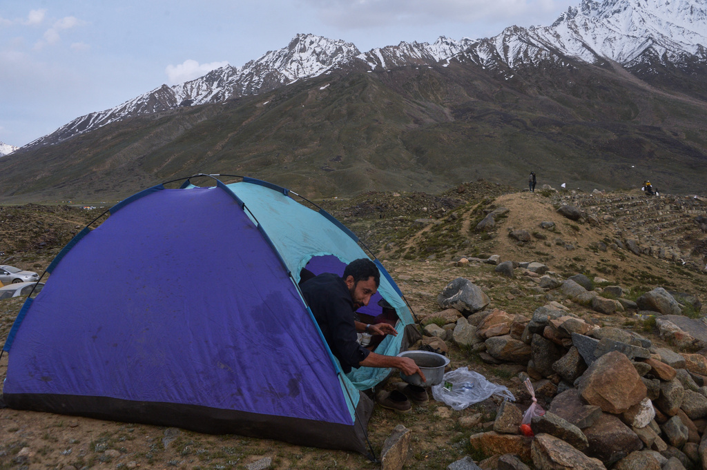 A spectator washes a dish after preparing tea in his tent during the three-day annual Shandur Polo Festival in Shandur Pass, in the Ghizer district of Gilgit-Baltistan, northern Pakistan, Friday, June 12, 2026. (AP Photo/Zubair Abbasi)