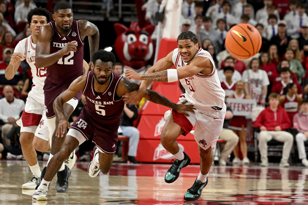 Texas A&M guard Jacari Lane, left, and Arkansas guard Darius Acuff Jr., right, go after a loose ball during an NCAA college basketball game Wednesday, Feb. 25, 2026, in Fayetteville, Ark. (AP Photo/Michael Woods)