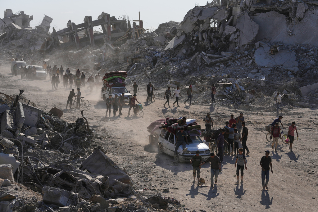 Displaced Palestinians with their belongings pass by destroyed buildings as they return to their homes in the Zeitoun neighborhood of Gaza City, Friday, Oct. 10, 2025, after Israel and Hamas agreed to pause their war and release remaining hostages. (AP Photo/Jehad Alshrafi)