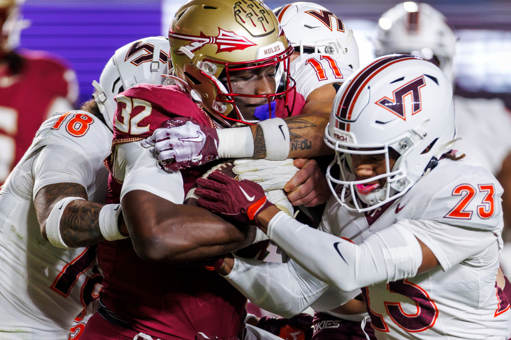 Florida State running back Ousmane Kromah (32) is stopped by Virginia Tech safety Isaiah Cash (18) and cornerback Thomas Williams (23) during the first half of an NCAA college football game, Saturday, Nov. 15, 2025, in Tallahassee, Fla. (AP Photo/Colin Hackley)