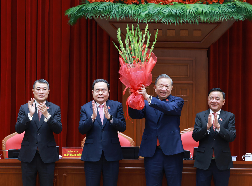 Vietnam's General Secretary of the Communist Party To Lam, second right, holds up a bouquet after being re-elected to the position following a National Congress in Hanoi, Vietnam, Friday, Jan. 23, 2026. (Hoang Thong Nhat/VNA via AP)