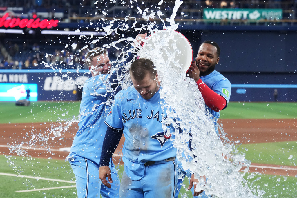 Toronto Blue Jays' Daulton Varsho is doused by Myles Straw (left) and Vladimir Guerrero Jr. after hitting a walk-off grand slam against the Tampa Bay Rays during 10th inning MLB baseball action in Toronto on Wednesday, May 13, 2026. (Nathan Denette/The Canadian Press via AP)
