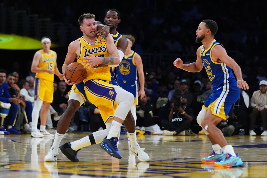 Los Angeles Lakers' Luka Dončić, left, is defended by Golden State Warriors guard Jonathan Kuminga during the first half of an NBA basketball game Tuesday, Oct. 21, 2025, in Los Angeles. (AP Photo/Ethan Swope)