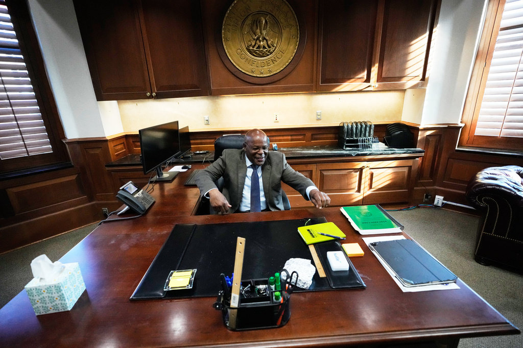 Calvin Duncan, left, an exoneree who was elected Orleans Parish clerk of criminal court, gets behind his desk on the first day of his term, Monday, May 4, 2026, in New Orleans. (AP Photo/Gerald Herbert)