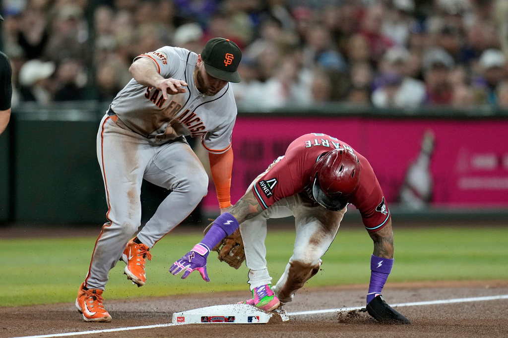 Arizona Diamondbacks' Ketel Marte, right, steals third base as San Francisco Giants third baseman Casey Schmitt, left, applies a late tag during the fourth inning of a baseball game, Wednesday, July 1, 2026, in Phoenix. (AP Photo/Ross D. Franklin)