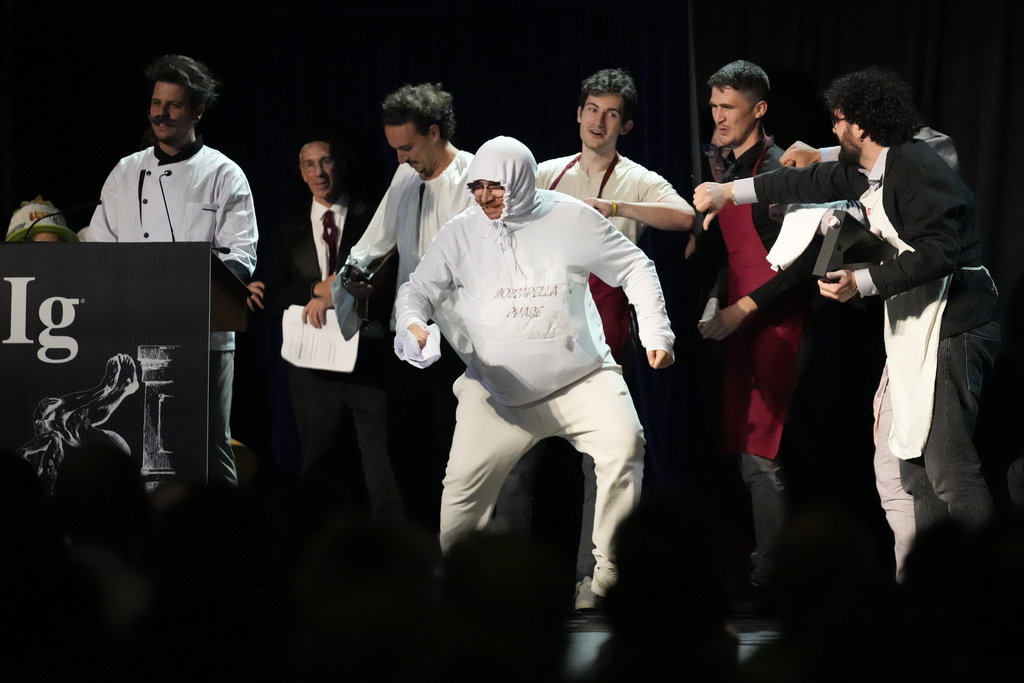 The Ig Nobel Prize for nutrition is accepted by Daniele Dendi, Gabriel H. Segniagbeto, Roger Meek, and Luca Luiselli, for studying the extent to which a certain kind of lizard chooses to eat certain kinds of pizza, Thursday, Sept. 18, 2025, in Boston. (AP Photo/Robert F. Bukaty)