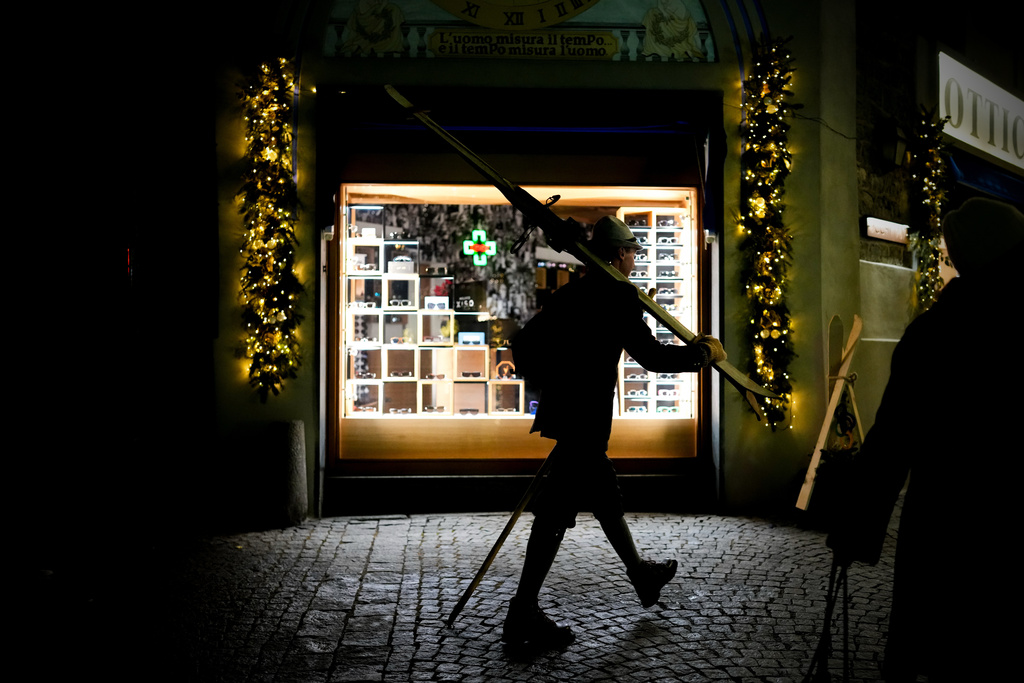 A person carries wooden skis as they walk to watch the opening ceremony of the 2026 Winter Olympics at Piazza Cavour, Friday, Feb. 6, 2026, in Bormio, Italy. (AP Photo/Julia Demaree Nikhinson)
