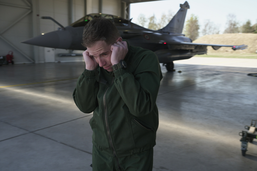 French air force Commander Dorian (surname withheld by the French military) uses his hands to shield his ears from the scream of the jet engines of a Rafale fighter preparing to take off from the Siauliai Air Base in Lithuania on a NATO air-policing mission on Monday, April 20, 2026. (AP Photo/John Leicester)