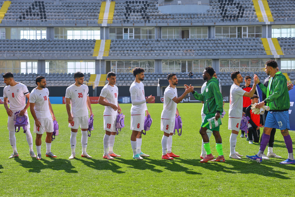 Iran's players, holding school bags symbolizing children allegedly killed in a U.S. strike on a school in Minab, greet Nigeria's players before a friendly soccer match, in Antalya, southern Turkey, Friday, March 27, 2026. (AP Photo/Riza Ozel)