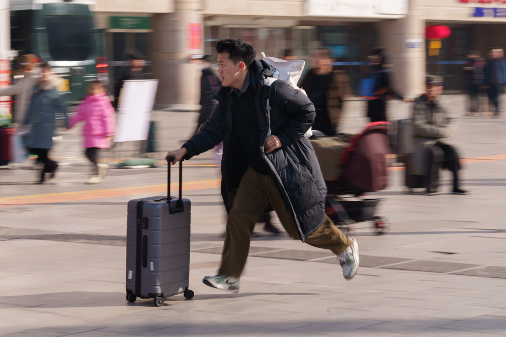 A man runs while pulling a suitcase at a railway station as people return home during the Lunar New Year holiday in Beijing, China, Tuesday, Feb. 10, 2026. (AP Photo/Vincent Thian)