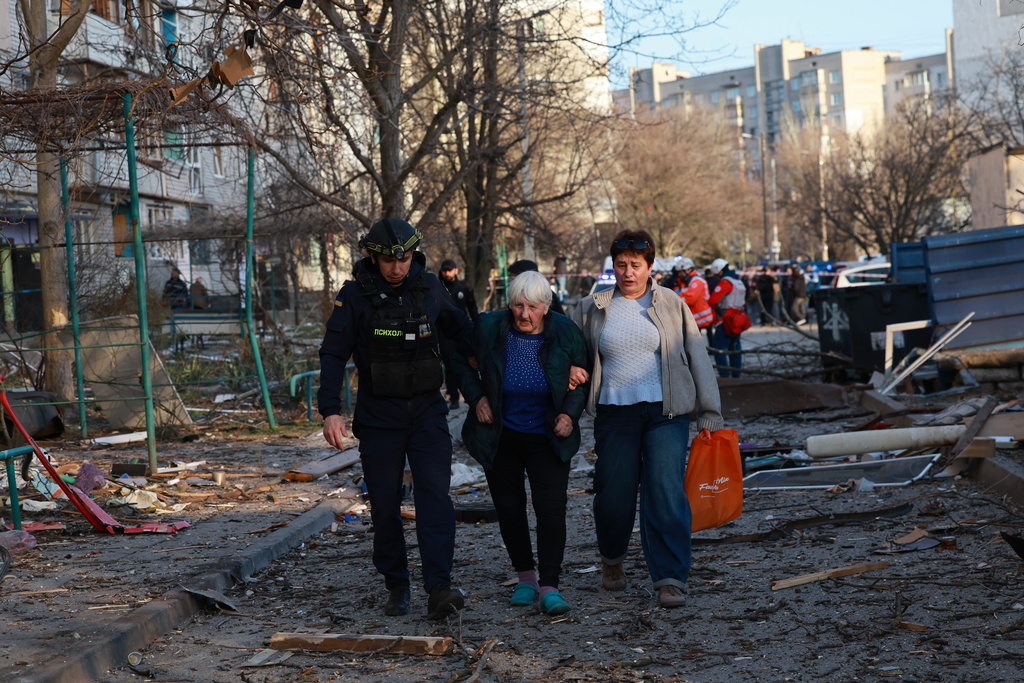 A rescuer helps an elderly woman to leave her home damaged by Russian aerial guided bomb in Zaporizhzhia, Ukraine, Saturday, March 14, 2026. (AP Photo/Kateryna Klochko)