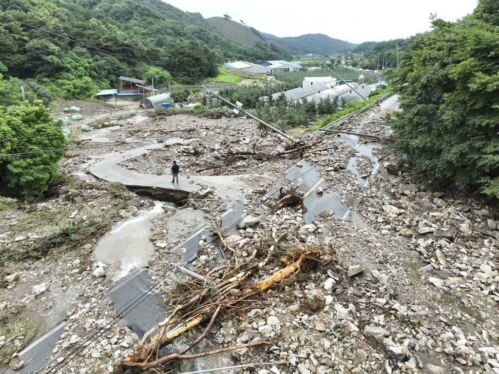 A road is covered with earth and rocks brought by a nearby landslide due to heavy rain at a village in Yesan, South Korea, Thursday, July 17, 2025. (Yoo Hyung-seok/Yonhap via AP)