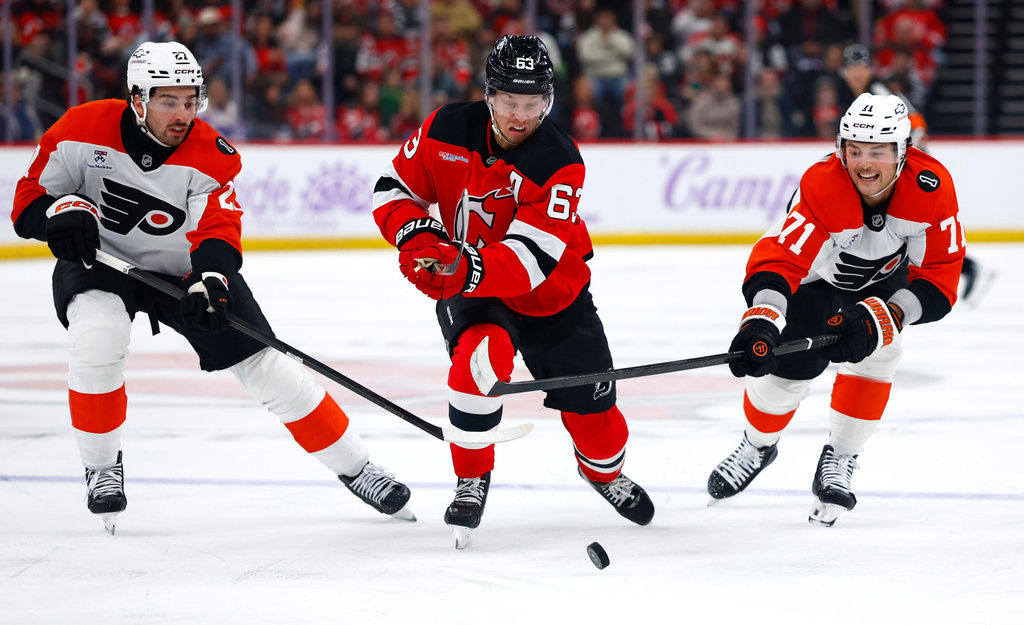 New Jersey Devils left wing Jesper Bratt (63) plays the puck against Philadelphia Flyers left wing Noah Cates (27) and right wing Tyson Foerster (71) during the second period of an NHL hockey game, Saturday, Nov. 29, 2025, in Newark, N.J. (AP Photo/Noah K. Murray)