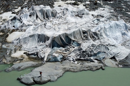 FILE - Matthias Huss, of the Federal Institute of Technology in Zurich and glacier monitoring group GLAMOS, stands at the Rhone Glacier that is partially covered with sheets near Goms, Switzerland, on June 10, 2025. (AP Photo/Matthias Schrader, File) FILE - Matthias Huss, of the Federal Institute of Technology in Zurich and glacier monitoring group GLAMOS, stands at the Rhone Glacier that is partially covered with sheets near Goms, Switzerland, on June 10, 2025. (AP Photo/Matthias Schrader, File)