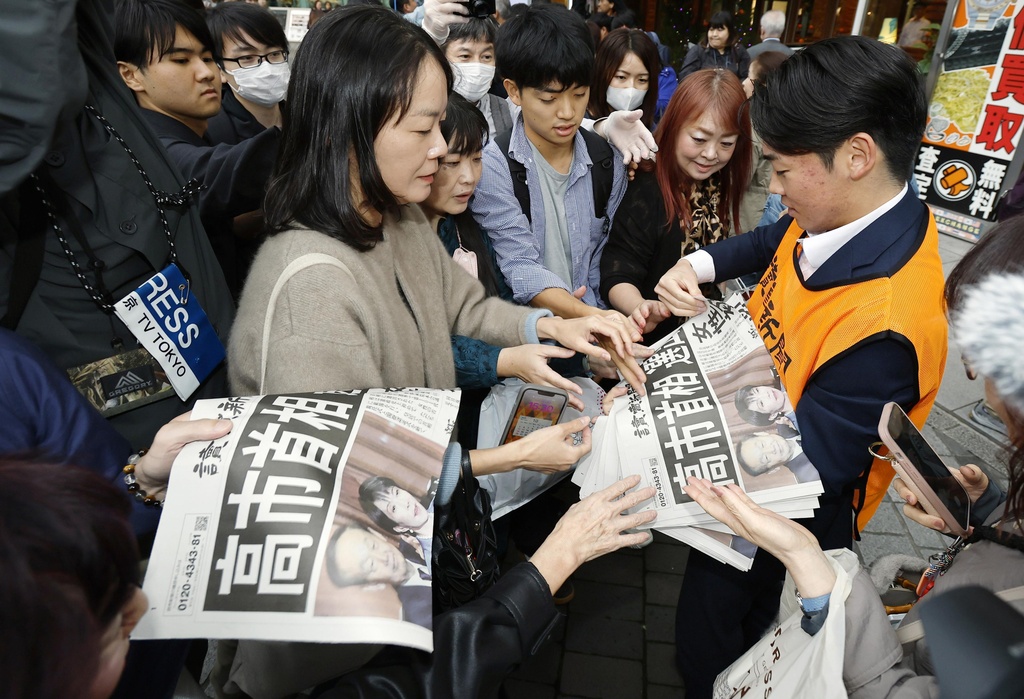 A Japanese newspaper staffer distributes copies of the extra issue on Sanae Takaichi being elected as Japan's first female prime minister, in Tokyo, Tuesday, Oct. 21, 2025. (Masanori Kumagai/Kyodo News via AP)