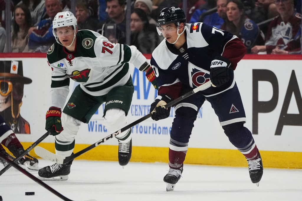 Colorado Avalanche defenseman Sam Malinski, front, passes the puck as Minnesota Wild center Nico Sturm pursues in the second period of an NHL hockey game, Sunday, March 8, 2026, in Denver. (AP Photo/David Zalubowski)