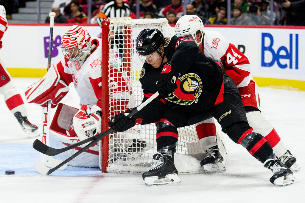 Ottawa Senators' Fabian Zetterlund (20) tries to wrap the puck around Detroit Red Wings' goaltender John Gibson, left, (36) during second-period NHL hockey game action in Ottawa, Ontario, Monday, Jan. 5, 2026. (Spencer Colby/The Canadian Press via AP)